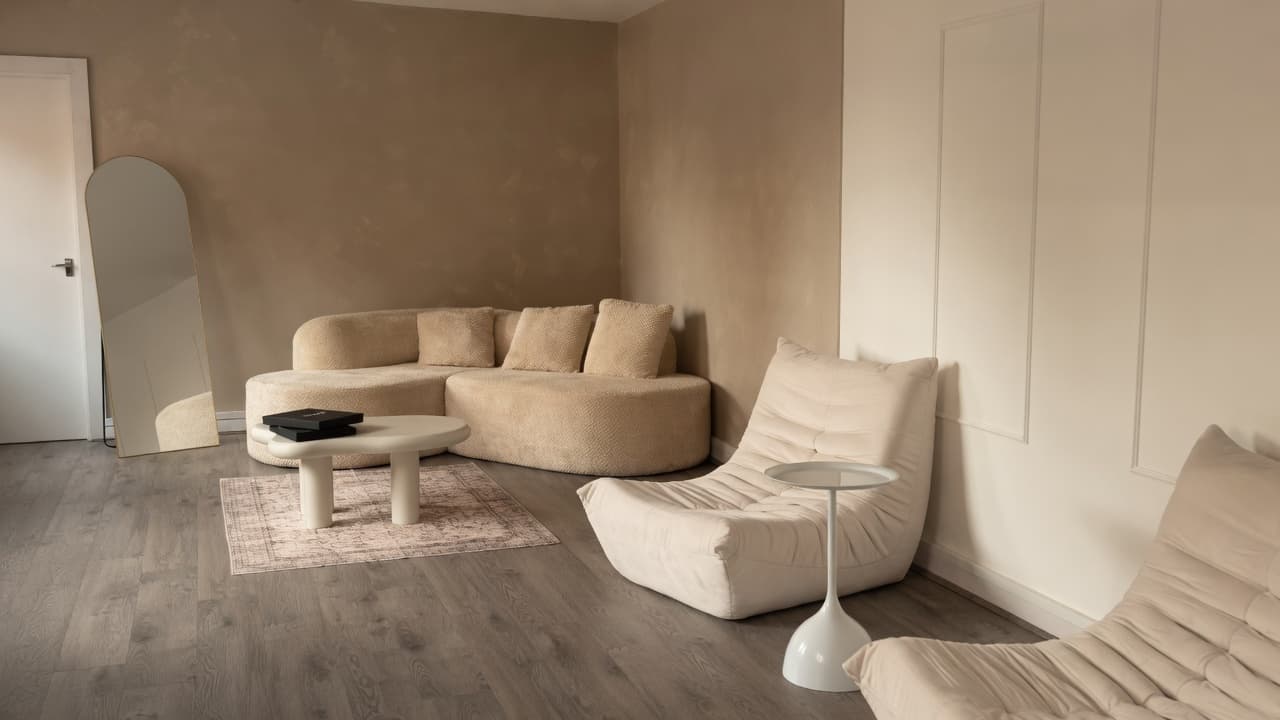 The Content Suite lounge — curved beige sofa, Togo chairs, arched mirror and cream wall panelling